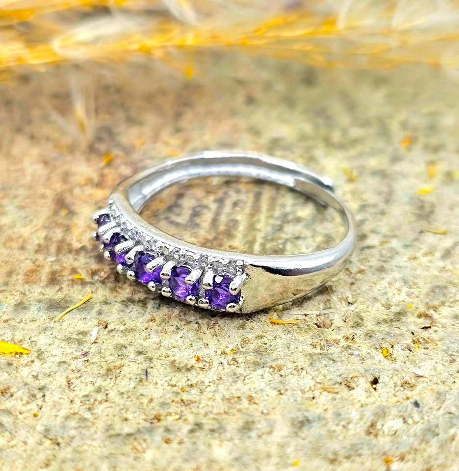 Silver adjustable ring with natural purple amethyst gemstones and clear accent stones displayed on a hand against a white background
