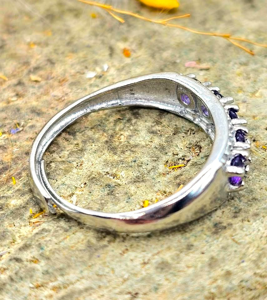 Silver adjustable ring with natural purple amethyst gemstones and clear accent stones displayed on a hand against a white background