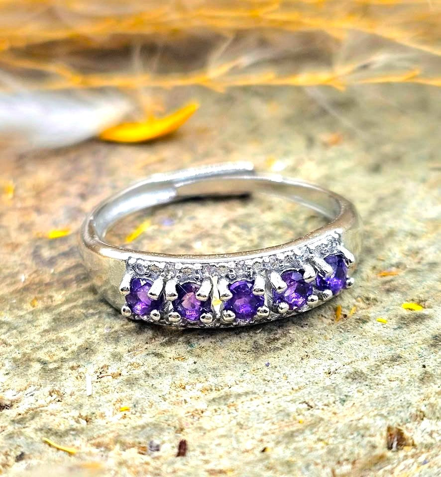 Silver adjustable ring with natural purple amethyst gemstones and clear accent stones displayed on a hand against a white background