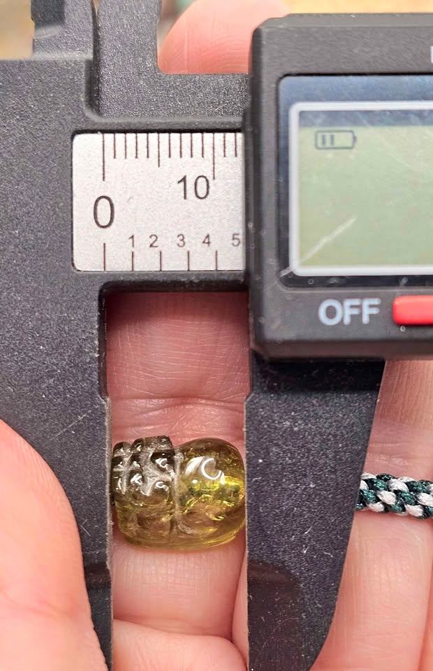 Natural Peridot carved Pi Xiu bracelet with white and dark green braided cord displayed on a white background.