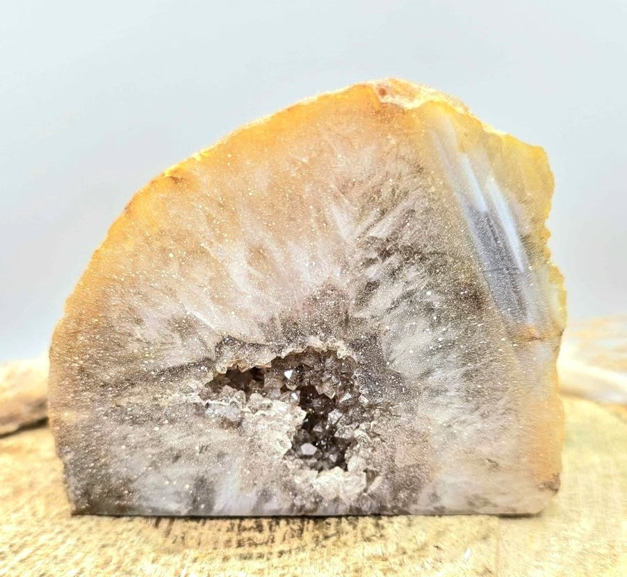 Natural quartz geode specimen with tan rough outer crust and sparkling white druzy crystal interior, standing upright.