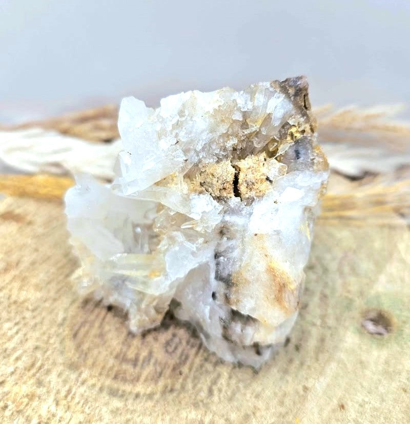 A natural crystal cluster featuring a prominent skull formation with clear quartz and beige mineral inclusions, displayed on a textured burlap surface in top view-My Aura Gemstones. 
