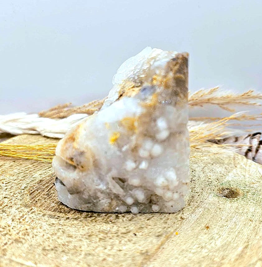 A natural crystal cluster featuring a prominent skull formation with clear quartz and beige mineral inclusions, displayed on a textured burlap surface in side -My Aura Gemstones.