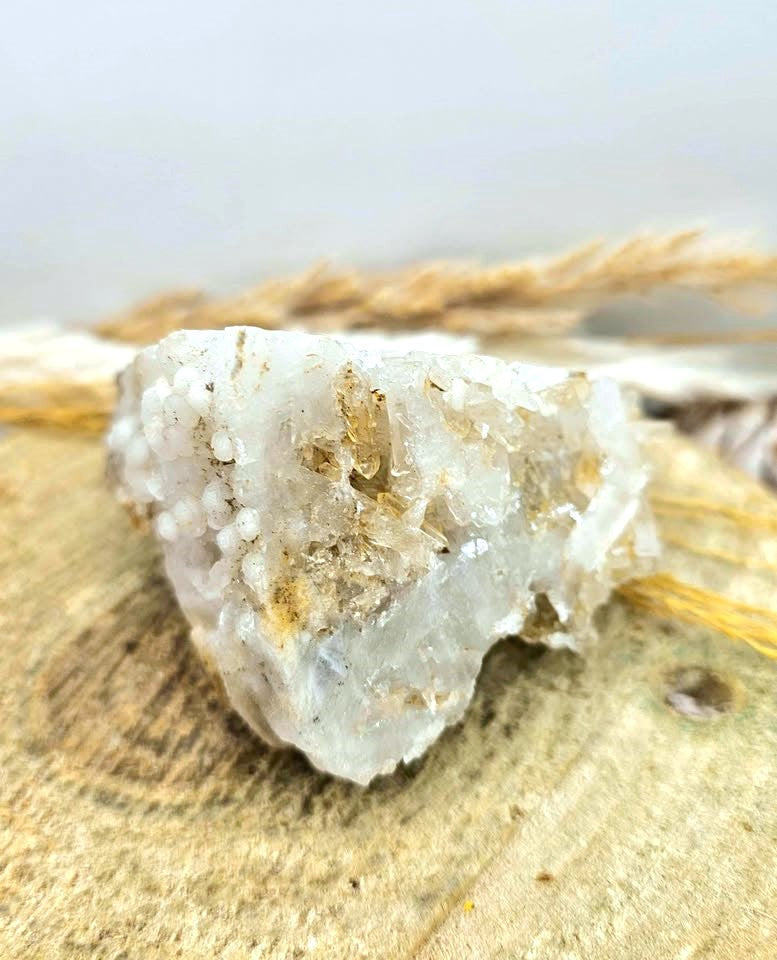A natural crystal cluster featuring a prominent skull formation with clear quartz and beige mineral inclusions, displayed on a textured burlap surface in bottom corner bottom-My Aura Gemstones.
