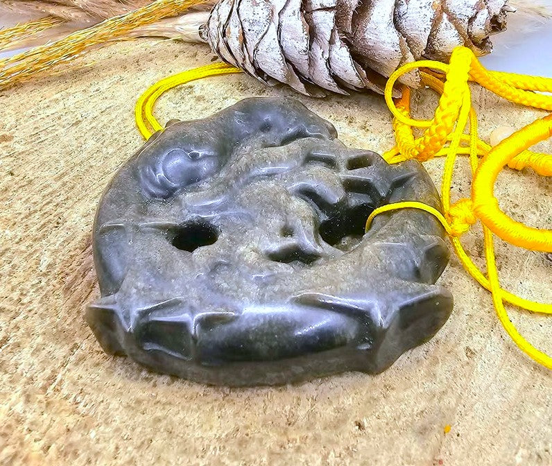 A gold obsidian stone carved  pendant featuring a nine tails fox on crescent moon, threaded with a bright yellow cord  in side view-My Aura Gemstones
