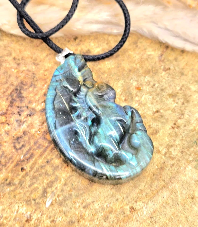 A carved labradorite  horse with a dragon pendant necklace featuring a detailed figure design with a shimmering blue-green iridescent  in top view- My Aura Gemstones. 