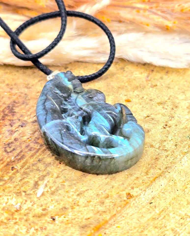 A carved labradorite  horse with a dragon pendant necklace featuring a detailed figure design with a shimmering blue-green iridescent at bottom view- My Aura Gemstones. 