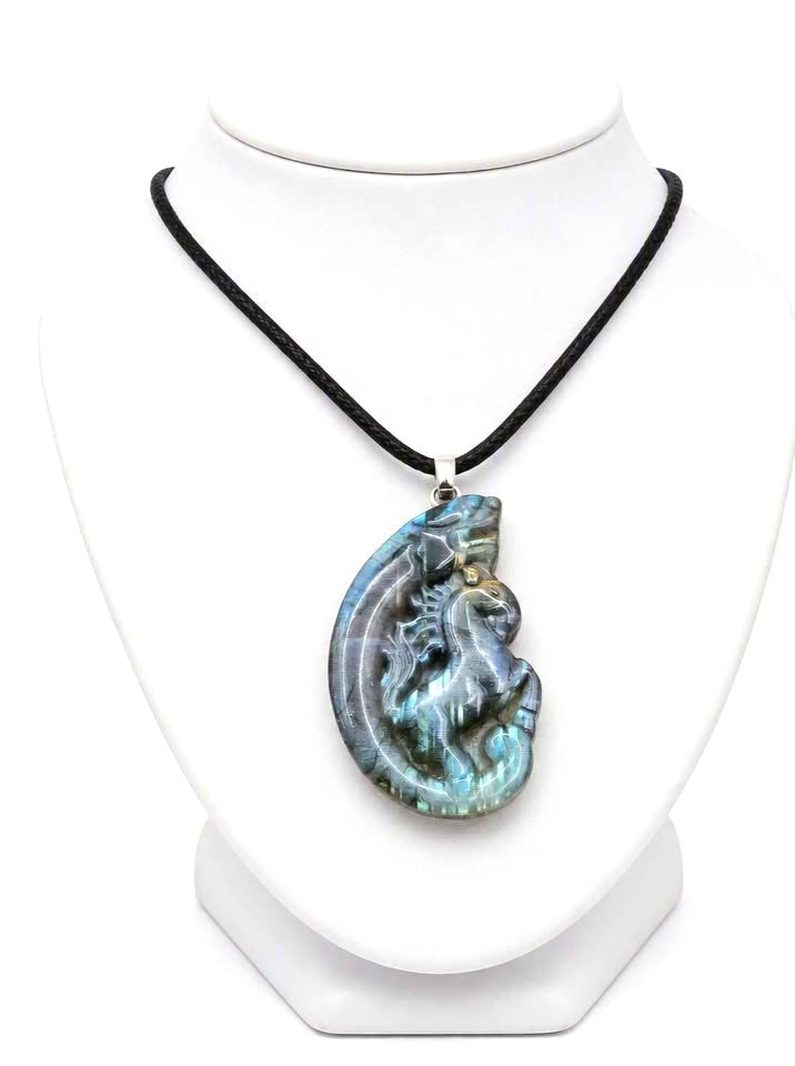A carved labradorite  horse with a dragon pendant necklace featuring a detailed figure design with a shimmering blue-green iridescent  in jewelry stand- My Aura Gemstones. 