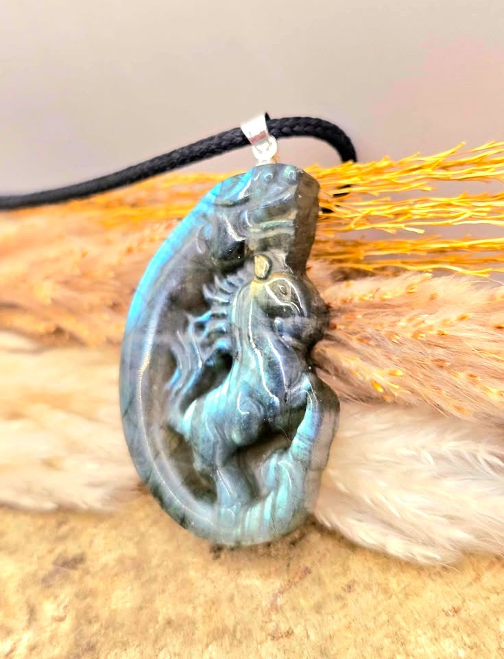A carved labradorite  horse with a dragon pendant necklace featuring a detailed figure design with a shimmering blue-green iridescent in side view - My Aura Gemstones. 