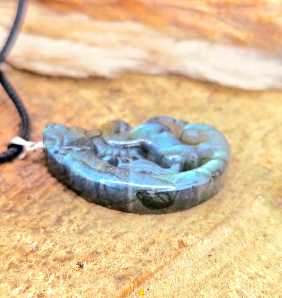 A carved labradorite  horse with a dragon pendant necklace featuring a detailed figure design with a shimmering blue-green iridescent in another side view- My Aura Gemstones. 