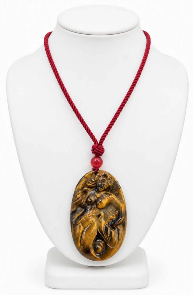 A carved oval pendant made of golden-brown tiger's eye stone carved mermaid,  pendant threaded on a red cord with a red bead display in jewelry stand-My Aura Gemstones