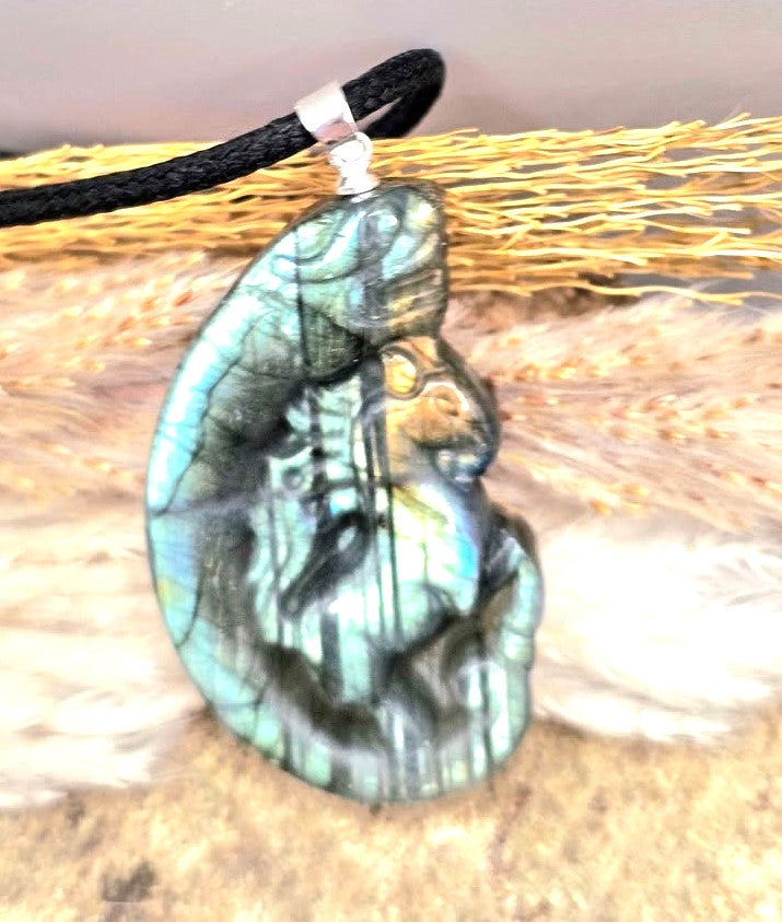 A carved labradorite  horse with a dragon pendant necklace featuring a detailed figure design with a shimmering blue-green iridescent at top view - My Aura Gemstones. 