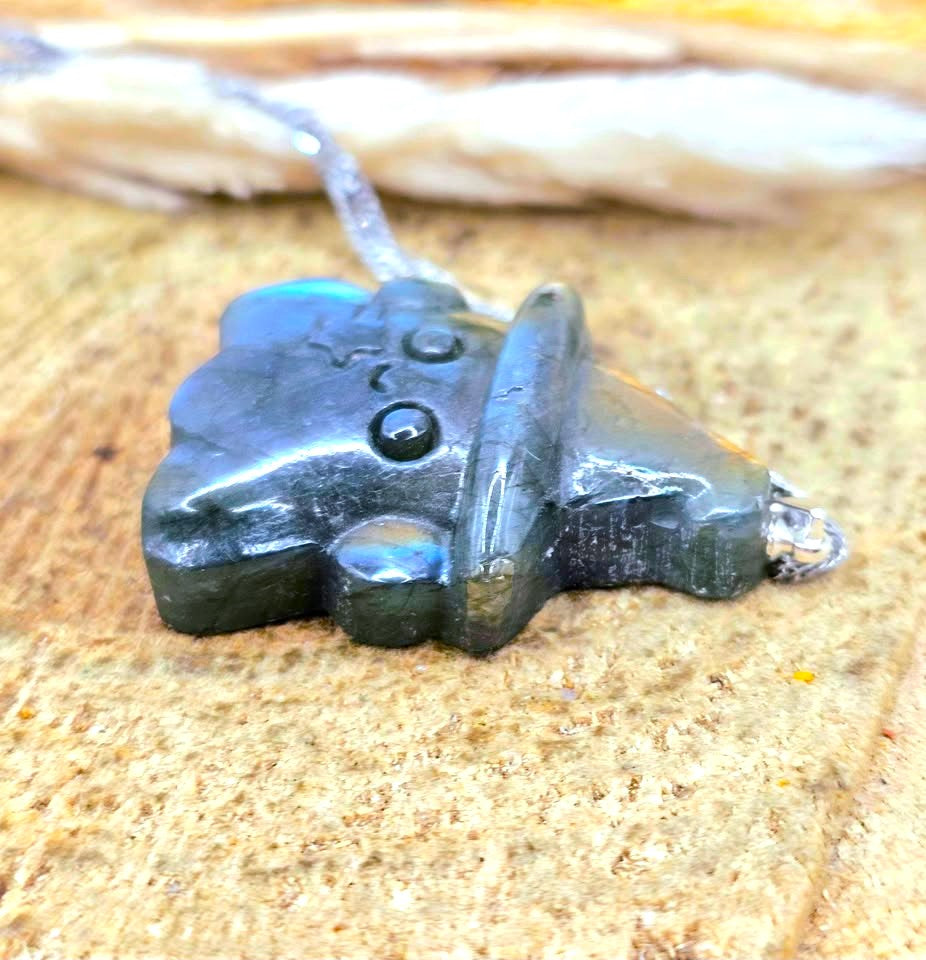 Natural labradorite carved ghost wizard-shaped pendant on wood slice at side view- My Aura Gemstones.