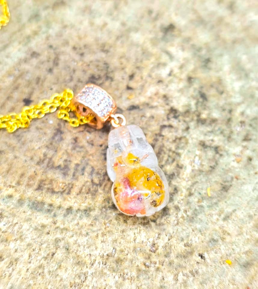 Natural Hematoid Koi quartz pendant necklace with a  pi xiu carving shaped containing yellow, orange inclusion.  Hanging from a gold chain with a pavé-set top, displayed on natural wood slice - My Aura Gemstones