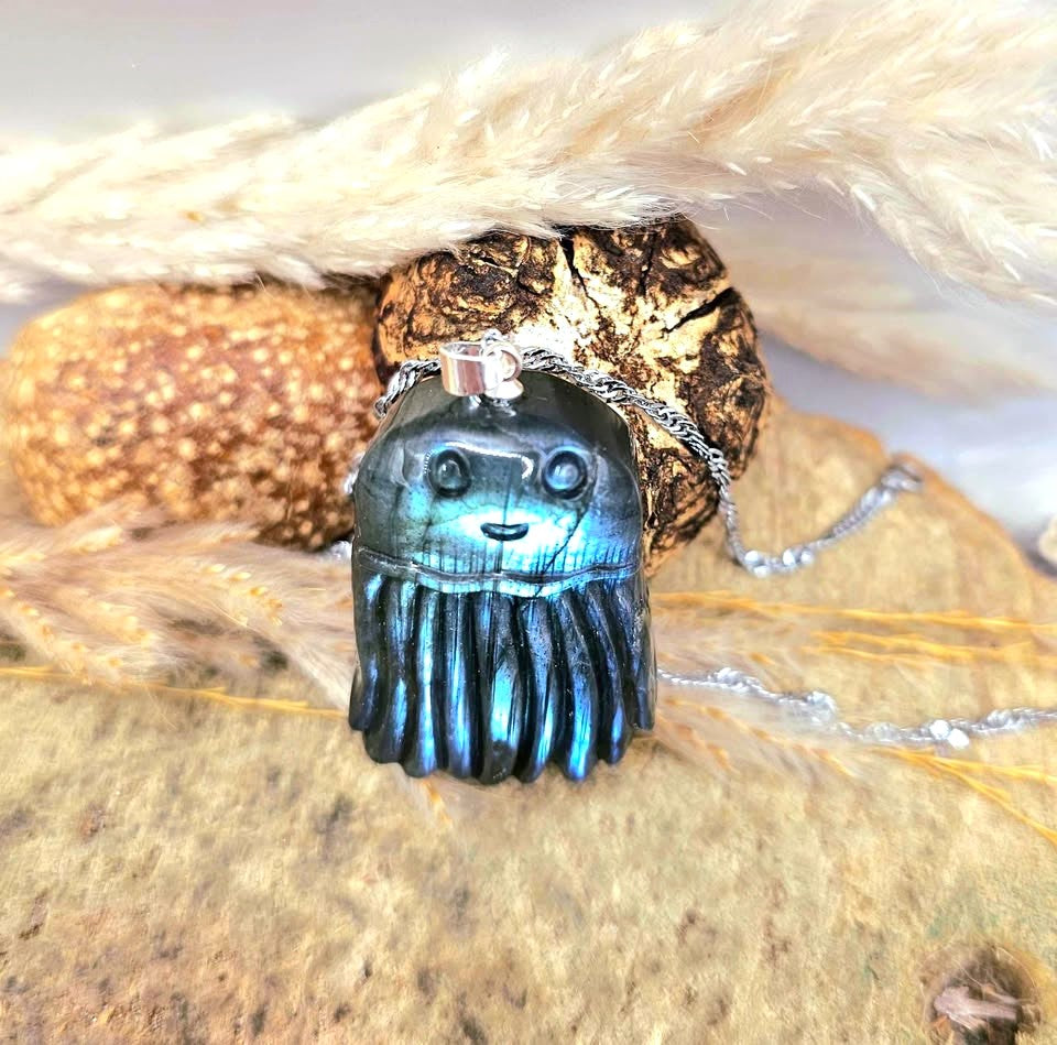 A blue iridescent jellyfish pendant necklace with a silver bail and chain, resting wood slice at top view-My Aura Gemstones