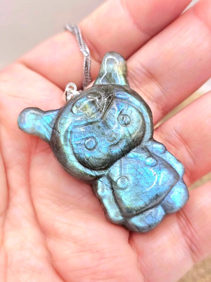 Natural labradorite pendant featuring a Kuromi‑inspired carving with smile and skull detail with silver chain displays on hand-My Aura Gemstones