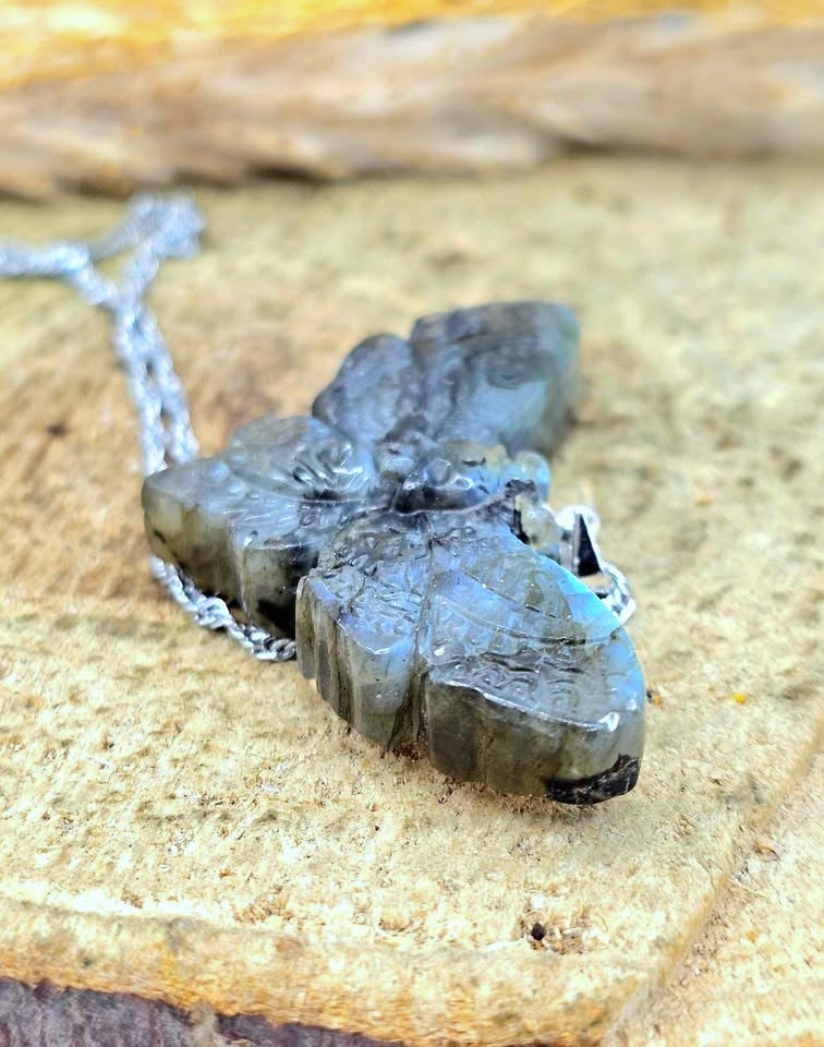 Natural Labradorite Moth With Skull Pendant Necklace displays on wood slice at front view-My Aura Gemstones