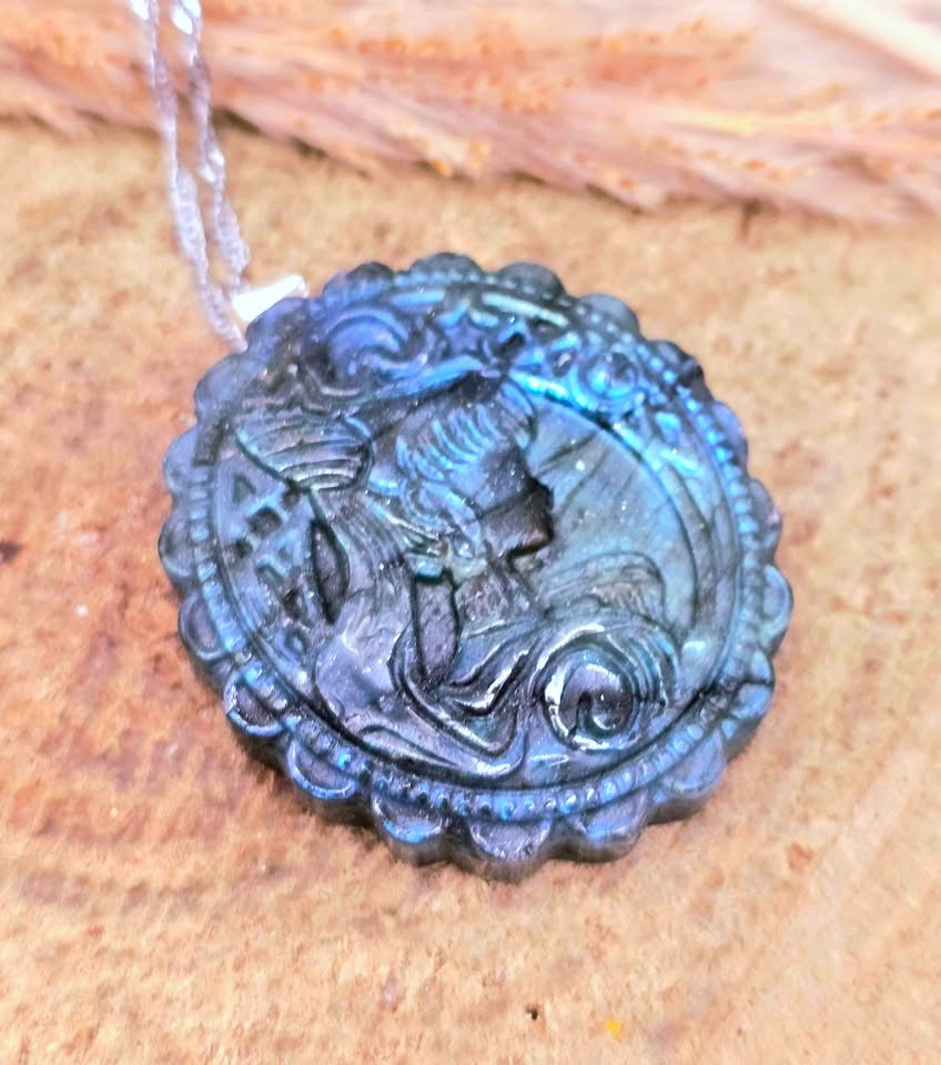 A round carved pendant or medallion with a raised profile portrait, shown hanging from a clear cord against a textured tan background.