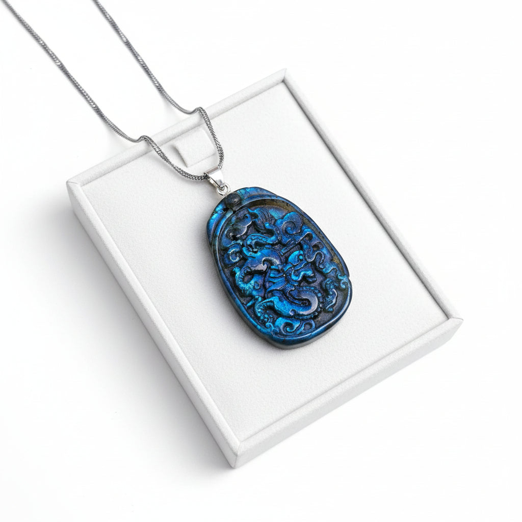 A carved blue pendant necklace featuring an intricate dragon design, resting on a textured tan surface with a white faux fur accent.