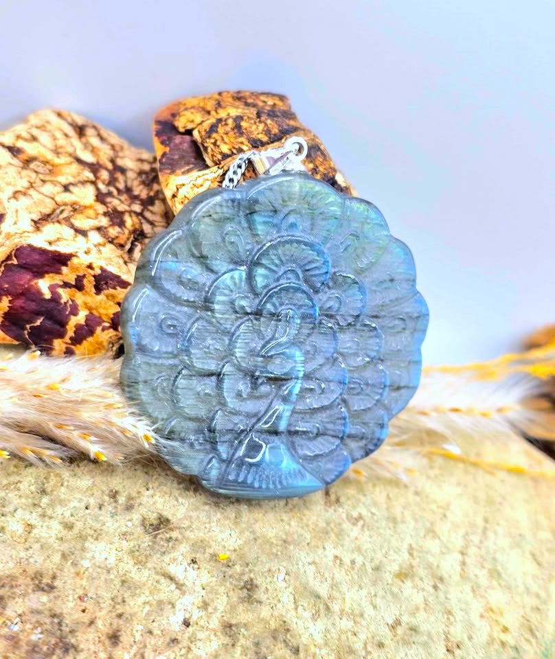 A carved blue stone pendant featuring an embossed figure, displayed on a textured surface with a patterned fabric and soft fur in the background.
