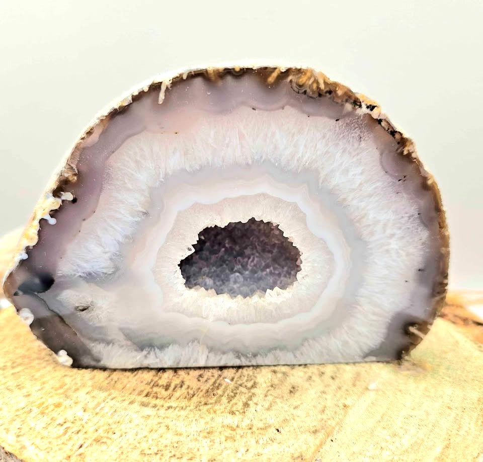 Natural druzy geode crystal with sparkling cavern displayed on white background, polished slice showing layered mineral bands-My Aura Gemstones