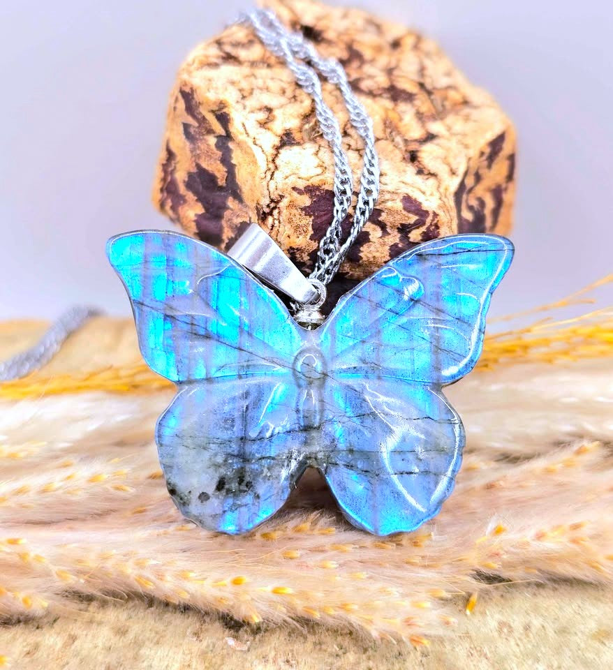 Natural Labradorite carved blue flash butterfly pendant displays on wood slice-My Aura Gemstones
