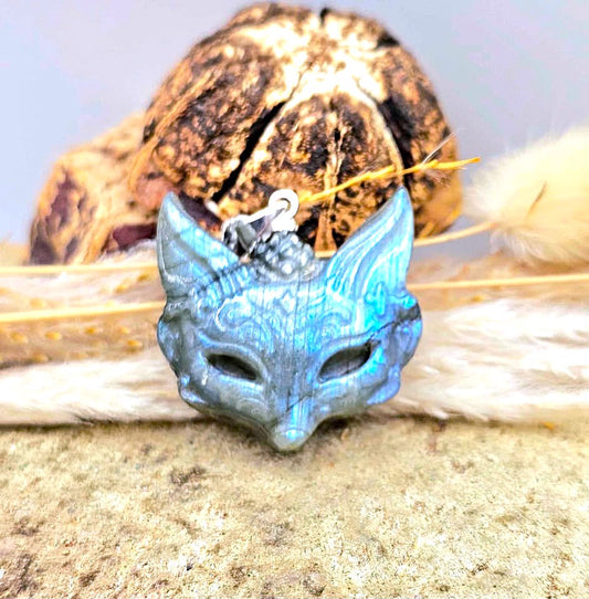 Labradorite blue iridescent fox head mask pendant with a silver lobster clasp, displayed against a rustic background with fur and dried leaves.-My Aura Gemstones