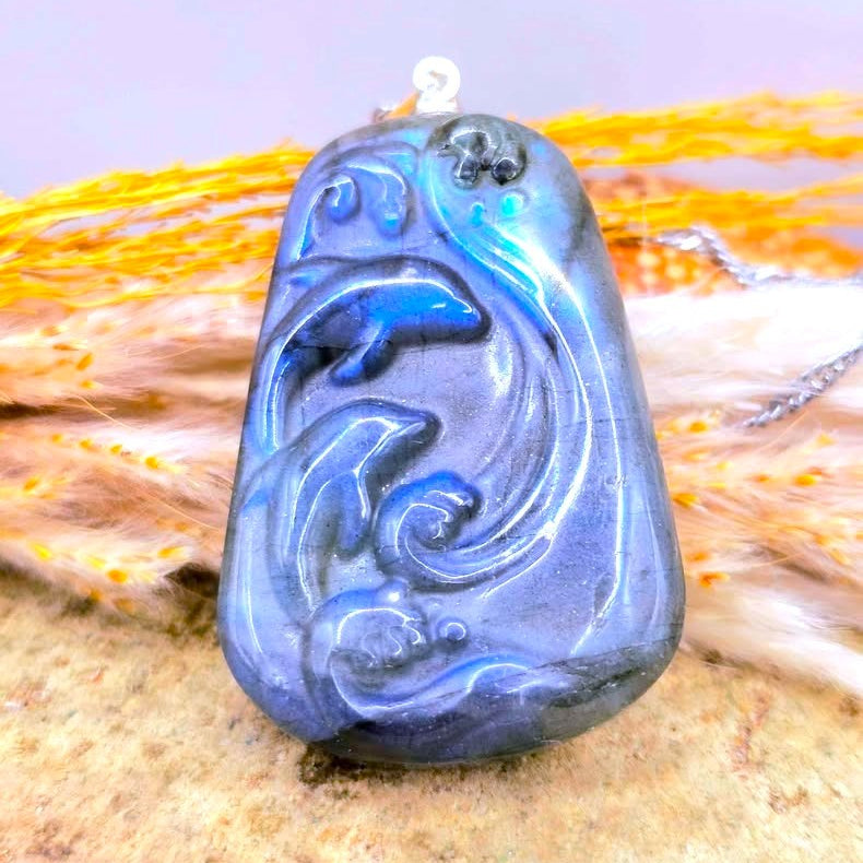 Natural labradorite carved two dolphins jumping from sea pendant necklace displays on wood slice- My Aura Gemstones