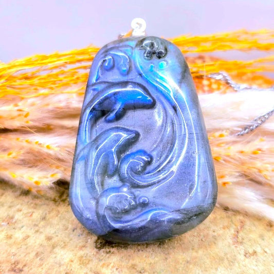 Natural labradorite carved two dolphins jumping from sea pendant necklace displays on wood slice- My Aura Gemstones