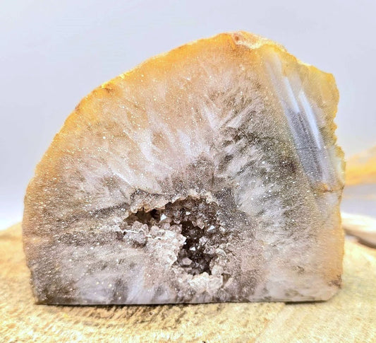 Natural quartz geode specimen with tan rough outer crust and sparkling white druzy crystal interior, standing upright.