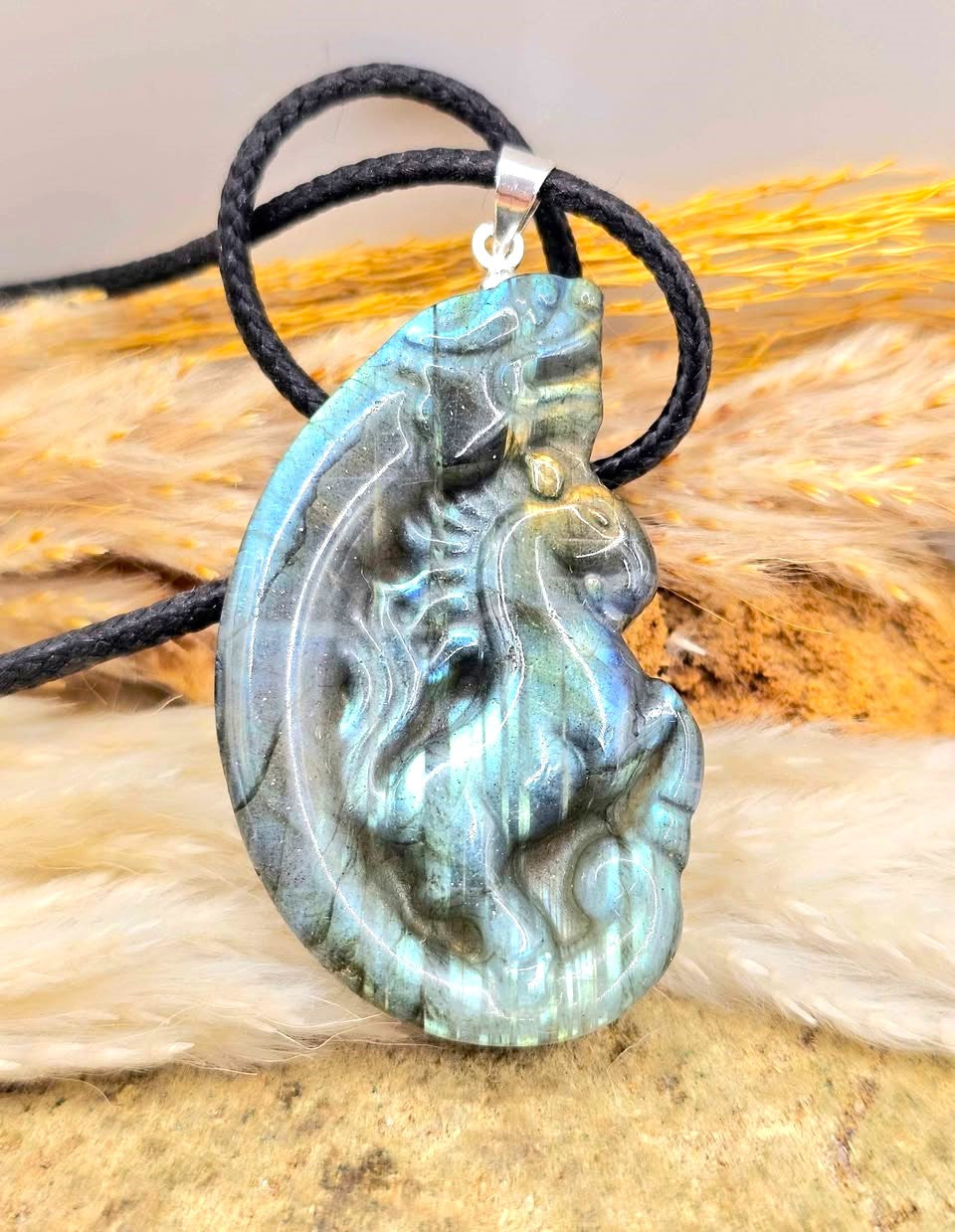 A carved labradorite  horse with a dragon pendant necklace featuring a detailed figure design with a shimmering blue-green iridescent - My Aura Gemstones. 