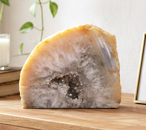 Natural quartz geode specimen with tan rough outer crust and sparkling white druzy crystal interior, standing upright.